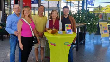 Bürgermeisterkandidatin Anette Westarp steht mit weiteren FDP-Mitgliedern an einem gelben FDP-Stand mit Schirm vor dem Unverpacktladen in Unterföhring.